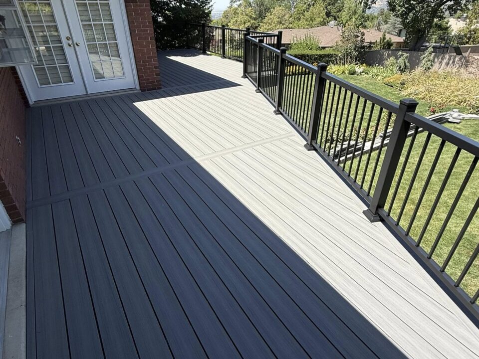 A beautiful grey deck in a Utah back yard with black railing.